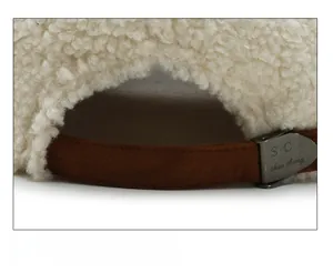 Close-up of lamb wool baseball cap with adjustable brown strap and metal buckle detail