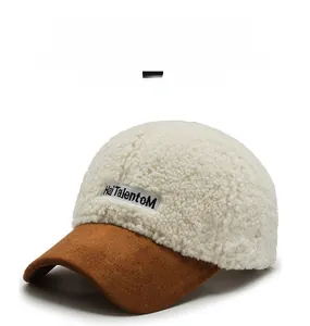 Detailed view of lambswool baseball cap with embroidered letter patch and brown suede brim