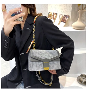 Dettaglio borsa grigia texture serpente con foulard in seta su tracolla dorata
