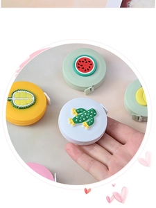 Close-up of various cartoon mini tape measures featuring watermelon and frog designs