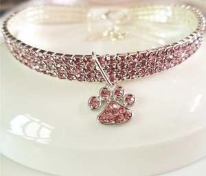 Macro view of pink rhinestone pet collar featuring three rows of crystals and a paw pendant