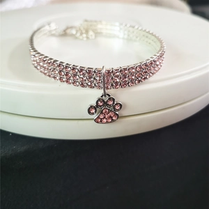 Macro shot of silver pet collar featuring three rows of pink rhinestones and a paw pendant