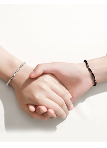 Close-up of Möbius silver chain and black woven rope bracelets worn by a couple