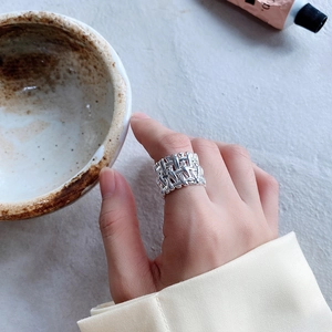 Close-up of a wide 925 sterling silver ring with textured woven bamboo pattern on finger