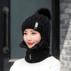 Détail de la cagoule en tricot noir avec pompon en fausse fourrure et col zippé chaud
