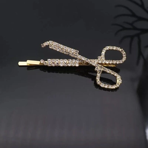 Macro detail of gold scissors hair clip encrusted with sparkling clear rhinestones