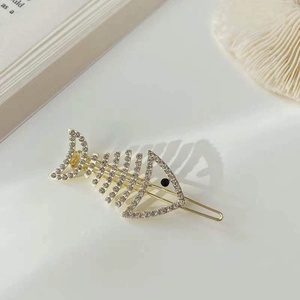 Macro detail of a golden fishbone hair clip with sparkling white rhinestones and black eye