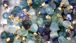 Bulk display of natural green fluorite raw stone pendants with gold metal caps