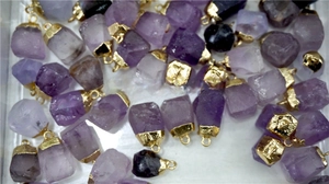 Macro detail of irregular natural amethyst pendants with gold-plated metal caps
