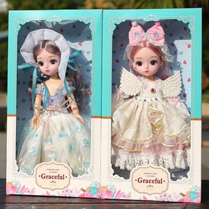 Detailed view of two boxed fashion dolls in blue and white dresses on an outdoor wooden table
