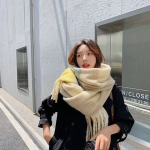 Close-up of thick plaid scarf with tassels in beige, yellow and camel hues