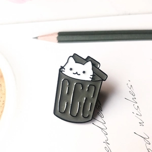 Detail of cute enamel cat in trash bin brooch on creative aesthetic stationery background