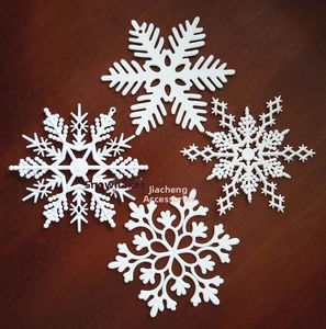 Macro view of four different 10cm white plastic snowflake ornaments on a rustic wood surface