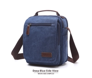 Detail view of deep blue canvas crossbody bag with leather handles and zip pockets