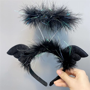 Close-up of black feather headband with devil wings and glowing tinsel detail