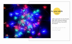 Close-up of multicolored star-shaped LED fairy lights with transparent wiring on black background