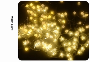 Close-up of warm yellow LED star and globe string lights glowing against dark background