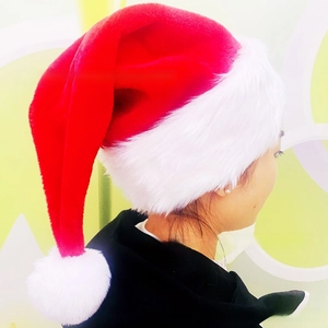 Detail view of the soft plush fabric and white pompom on this classic red Christmas hat