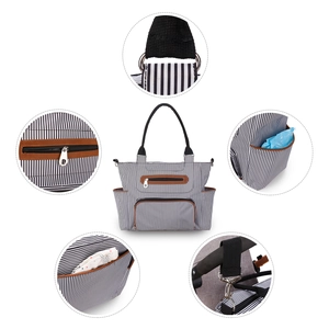 Detail view of multi-functional striped diaper bag showing hooks and zipper compartments