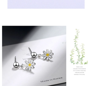 Close-up of silver daisy drop earrings with white petals and yellow centers on card
