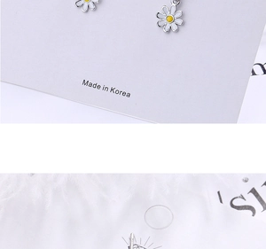 Close-up of sweet daisy stud earrings with white petals and yellow centers on a card