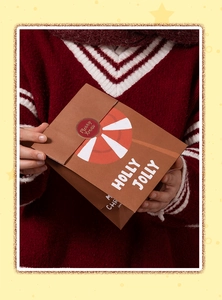 Close-up of brown Christmas paper gift bag with Merry Xmas sticker and festive pattern