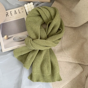 Detail shot of matcha green ribbed knit scarf on wool coat with cozy aesthetic lifestyle props