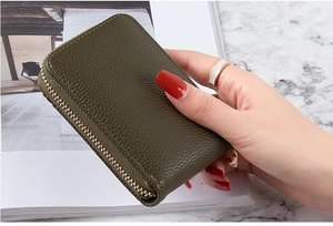 Olive green lychee leather card holder with gold zipper held in a model's hand