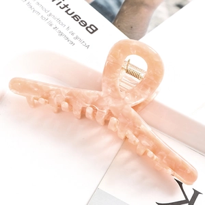 Macro shot of pink marble acetate hair claw clip with golden spring on magazine