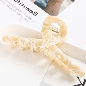 Detail of a cream amber marble acetate hair claw clip on a stylish magazine background