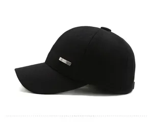 Detail view of the silver SPORTS metal emblem on a black thermal baseball cap for men