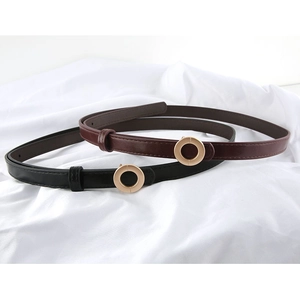 Detail of slim leather belts in black and brown with round gold buckles on white cloth