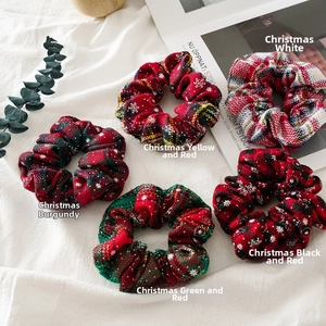 Close-up of five Christmas plaid hair scrunchies with snowflake patterns and soft texture