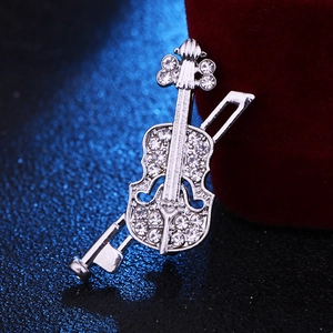 Gros plan d'une broche violon argentée avec cristaux scintillants sur surface bleue
