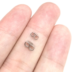 Close-up of stainless steel butterfly earring backs held for size reference