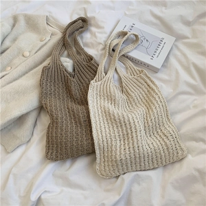 Hand-woven large knit tote bags in khaki and cream white shown on a soft white bedspread