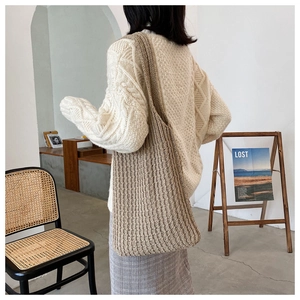 Textura de punto detallada del bolso tote tejido beige llevado por una modelo de moda