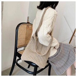 Detalle del bolso tote de punto grueso beige en una modelo en un entorno natural suave