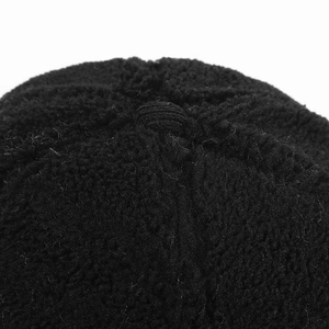 Detail shot of the top button and thick black sherpa fleece texture of the baseball cap