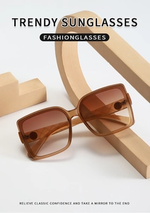 Detail view of large square frame sunglasses with brown gradient lenses on geometric props
