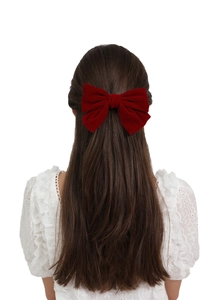 Back view of a model wearing a large red velvet bow hair clip with a spring mechanism