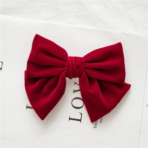 Detailed top view of a wine red velvet bow hair clip on a minimalist white backdrop