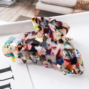 Detail of colorful ink-patterned acetate hair claw clip on a white tray