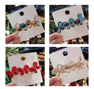 Detailed view of four crystal butterfly hair clips in various colors on display cards