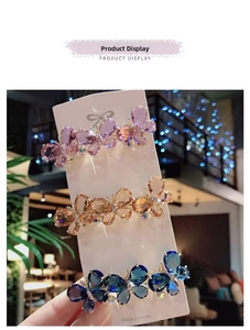 Detailed view of three butterfly hair clips in purple, gold, and blue with crystals