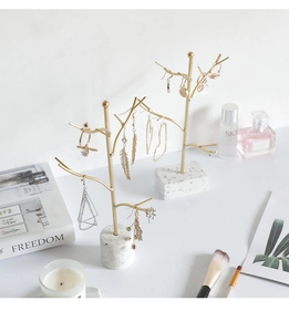 Detail of golden tree branch jewelry stand with white marble base for earrings