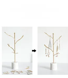 Detail eines goldenen Schmuckständers in Baumform mit weißem Marmorfuß für Ohrringe
