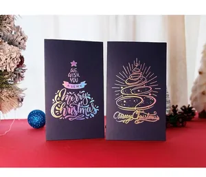 Detailed view of black laser foil Christmas cards with golden tree and red festive background