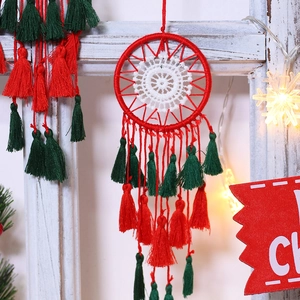 Close-up of handmade Christmas dreamcatcher with festive red and green cotton tassels