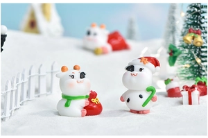 Close-up of cute Christmas cow figurines with holiday accessories in a snowy landscape
